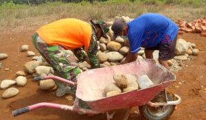 Siapkan Bahan Material, Sertu Deka Gusri Gotong Batu Ke Lokasi